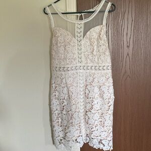 About knee length white lace dress with neutral underlay.